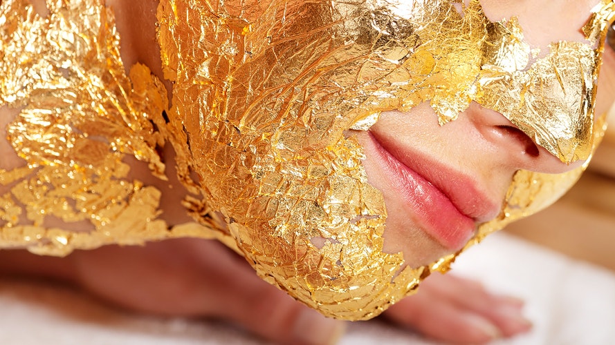 Woman getting face painted in gold